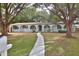 Charming single-story home with an arched entryway, a well-manicured lawn, and mature trees creating a picturesque setting at 2912 Pinecrest Way, Sarasota, FL 34239