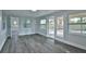 Bright living room featuring gray wood floors, white trim, and glass sliding doors to the back patio at 2912 Pinecrest Way, Sarasota, FL 34239