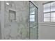 Close-up of the bright, white tiled shower with built in niche and glass door at 2912 Pinecrest Way, Sarasota, FL 34239