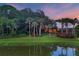 Idyllic backyard features lush greenery, mature trees, and a serene pond reflecting the sunset sky at 7620 Club Ln, Sarasota, FL 34238