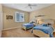 Bright bedroom with twin beds, light blue accents, a ceiling fan, and a sunny window creating a cheerful space at 7620 Club Ln, Sarasota, FL 34238