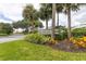 Community entrance sign surrounded by lush landscaping and mature palm trees under a cloudy sky at 7620 Club Ln, Sarasota, FL 34238