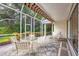This screened lanai features outdoor seating and views of the lush tropical landscaping and backyard at 7620 Club Ln, Sarasota, FL 34238