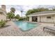Community pool featuring a cabana, paved surround, lounge chairs, and lush tropical landscaping at 7620 Club Ln, Sarasota, FL 34238