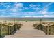 Scenic beach view down wooden stairs with the ocean, sand, and a few people enjoying the sunny day at 929 Suncrest Ln, Englewood, FL 34223