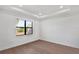 Bright bedroom with hardwood floors, tray ceiling and a large window offering plenty of natural light at 18773 Dayspring Pl, Venice, FL 34293
