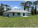 A view of the backyard of a single-story home showing the green lawn and the back of the house at 5018 Wagon Wheel Dr, North Port, FL 34291