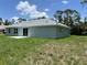 Backyard view showcasing the house, sliding glass doors, and lush green grass at 5018 Wagon Wheel Dr, North Port, FL 34291