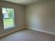 Well lit bedroom with neutral carpet, baseboard trim, and single-paned window overlooking green landscaping at 5018 Wagon Wheel Dr, North Port, FL 34291