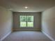 Well lit bedroom with neutral carpet, baseboard trim, and double-paned window overlooking lush green landscaping at 5018 Wagon Wheel Dr, North Port, FL 34291