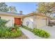 Charming home with a stone facade, red door, manicured plants, and an attached garage at 7607 9Th Avenue Nw Dr, Bradenton, FL 34209