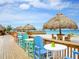 Beachfront view with colorful seating and thatched umbrellas at 303 48Th W St, Bradenton, FL 34209