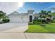 Modern home exterior with three-car garage and lush landscaping at 12734 Rainwashed Loop, Parrish, FL 34219