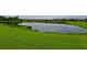 Community lakefront view with lush green grass and homes reflecting on the water at 7114 Quiet Creek Dr, Bradenton, FL 34212