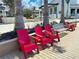 Outdoor seating area showcasing red Adirondack chairs along a modern building under a sunny blue sky at 225 Brighton Ct, Englewood, FL 34223