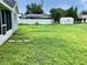 Large, grassy backyard featuring a white storage shed and partial views of a pool at 5278 Sabrina Ter, North Port, FL 34286
