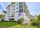 Multi-story condo with manicured lawn and tropical landscaping. Parking garage visible on the left at 236 Hidden Bay Dr # 301, Osprey, FL 34229