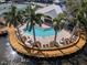 Aerial view of a community pool surrounded by palm trees, lounge chairs, and a wooden deck on the water at 236 Hidden Bay Dr # 301, Osprey, FL 34229