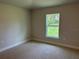Cozy bedroom featuring a window with a lush green view and neutral carpeting at 5661 Gaffney Rd, North Port, FL 34286