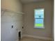 Functional laundry room with tile flooring, window, and shelving for storage and organization at 5661 Gaffney Rd, North Port, FL 34286