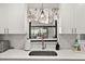 Kitchen features white cabinets, a farmhouse sink, and a window overlooking the backyard at 10194 Thames Ave, Englewood, FL 34224