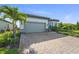 One-story home featuring a paver driveway, two-car garage, manicured lawn, and tropical landscaping at 14480 Eagle Branch Dr, Nokomis, FL 34275
