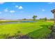 Expansive green backyard with a tranquil pond view under a clear blue sky at 3118 Tramonto Ct, Bradenton, FL 34211