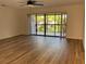 Open-concept living room with wood-look floors, ceiling fan, and access to the outdoor balcony at 3810 75Th W St # 116, Bradenton, FL 34209