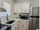 Bright kitchen featuring white cabinets, stainless steel appliances, updated counter tops, and a modern faucet at 5925 Todd St # D-21, Bradenton, FL 34207