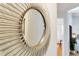 A close-up of a stylish, round, sunburst mirror hanging in a hallway with a glimpse into other rooms at 5306 19Th W Ave, Bradenton, FL 34209
