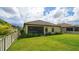 Large backyard with screened patio, lush landscaping and a white fence at 220 Capriana Ct, Nokomis, FL 34275