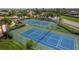 Aerial view of pristine blue and green tennis courts, enhancing the community's recreational appeal amid lush landscaping at 2995 Bravura Lake Dr, Sarasota, FL 34240