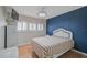 A bright bedroom with a blue accent wall, wood floors and a view to the window at 1026 Bird Bay Way # 276, Venice, FL 34285