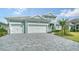 Three-car garage with paver driveway and landscaping at 12420 Destin Loop, Venice, FL 34293