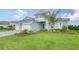 Two-story house with light teal exterior, three car garage, and landscaped lawn at 12420 Destin Loop, Venice, FL 34293