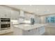 Bright kitchen boasts white cabinets, stainless steel appliances, and a large island at 12420 Destin Loop, Venice, FL 34293