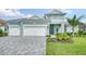 Two-story home with light teal exterior, three car garage, and landscaping at 12420 Destin Loop, Venice, FL 34293