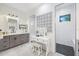 Spa-like bathroom with gray vanity, white subway tile shower, and patterned accent wall at 14219 Wenzel Ave, Port Charlotte, FL 33981