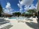 Community pool with lounge chairs, tables, and umbrellas, with palm trees and blue sky at 7818 33Rd E St, Sarasota, FL 34243