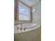 Close-up of a luxurious soaking tub with tile surround and a large window offering a view at 5120 Tidewater Preserve Blvd, Bradenton, FL 34208