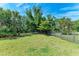 Spacious fenced in backyard with green grass, landscaping, and mature trees at 7572 Viola Loop, Lakewood Ranch, FL 34202