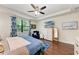 Bright bedroom featuring a ceiling fan, a flat-screen TV, and an accent chair with a picturesque window view at 7572 Viola Loop, Lakewood Ranch, FL 34202