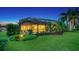 Backyard at dusk features a screened in patio, lush landscaping, and a view of palm trees at 12663 Fontana Loop, Bradenton, FL 34211