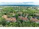 High aerial view showcases lush greenery, neighborhood homes with clay tile roofs, and distant water views at 264 Woods Point Rd, Osprey, FL 34229