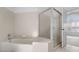 Bright bathroom featuring a bathtub and glass shower, tiled walls and open view to the bedroom with a window at 264 Woods Point Rd, Osprey, FL 34229