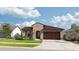 Tan house with brown wood garage door and lush landscaping at 8810 Windlass Cv, Parrish, FL 34219