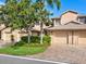 Tan colored townhouses with attached garages and landscaping at 5283 Heron Way # 204, Sarasota, FL 34231