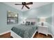Comfortable bedroom features a ceiling fan, hardwood floors, and bright natural light from a window at 14619 Leopard Creek Pl, Lakewood Ranch, FL 34202