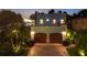 A nighttime view of the front exterior of a two-story home featuring a two-car garage and accent lighting at 1884 Grove St, Sarasota, FL 34239
