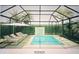 Relaxing pool area with sun loungers and a waterfall feature, enclosed with a glass roof and lush greenery at 1884 Grove St, Sarasota, FL 34239